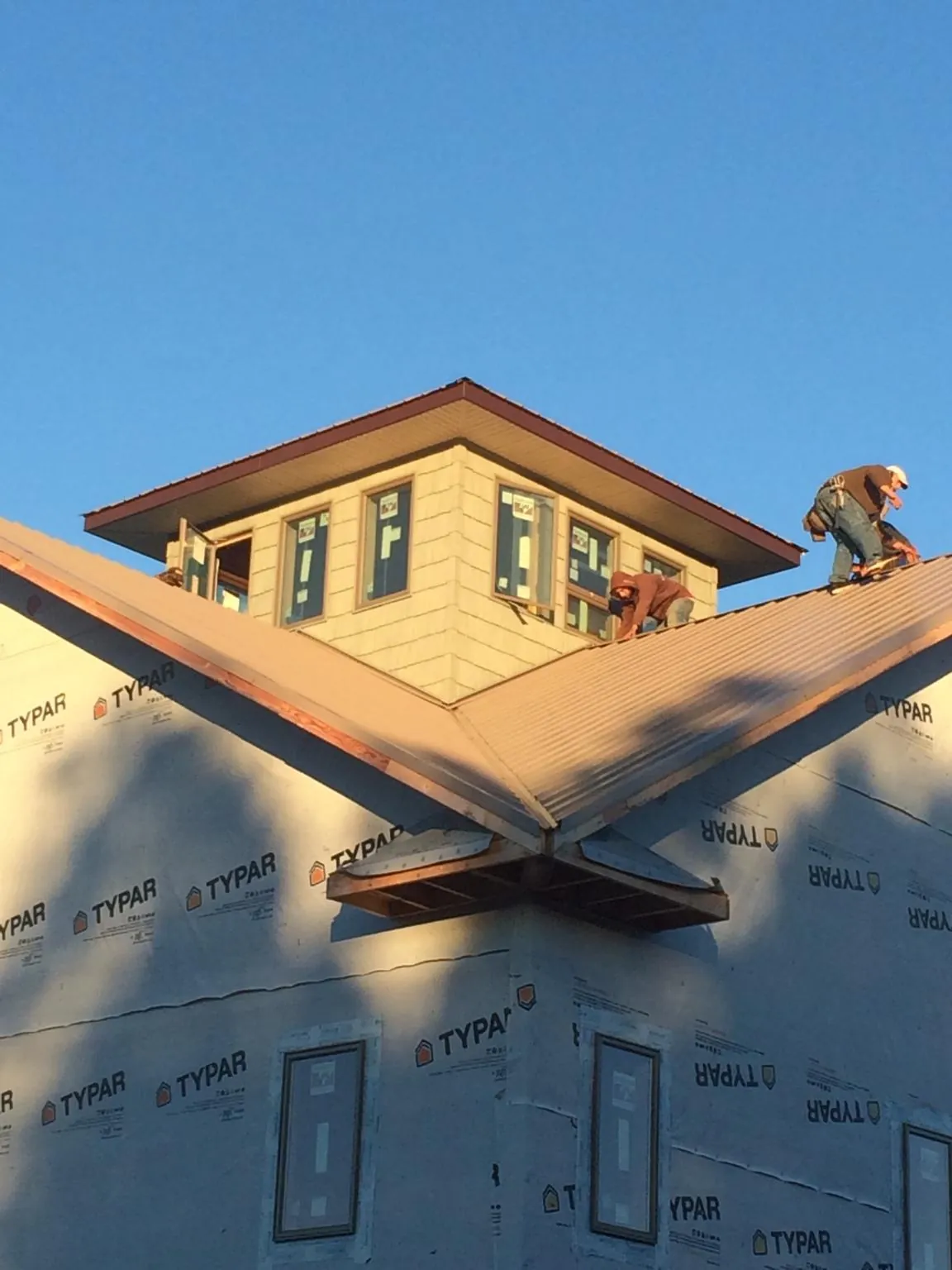 Roofers working around a rooftop cupola on a new metal roof at sunset — Roof Waterproofing in Upton by Roofing Brothers